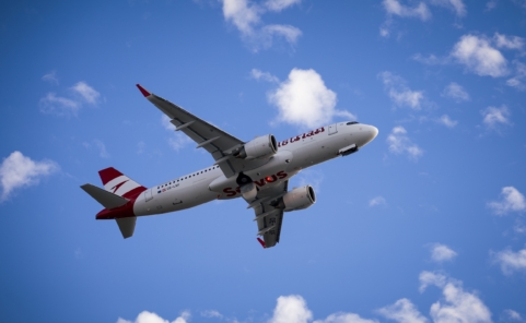 Airbus A320neo von Austrian Airlines im Flug, von unten vor blauem Himmel fotografiert.
