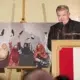 Cornelius Obonya spricht am Rednerpult. Links neben ihm zeigt Silvia Alessis Siegerfoto afghanische Frauen mit erhobenen Haartrocknern.