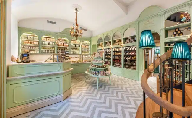 Mintgrüner Gerstner-Shop mit Verkaufsvitrinen, Warenregalen und Treppe zum ersten Stock im Palais Todesco.