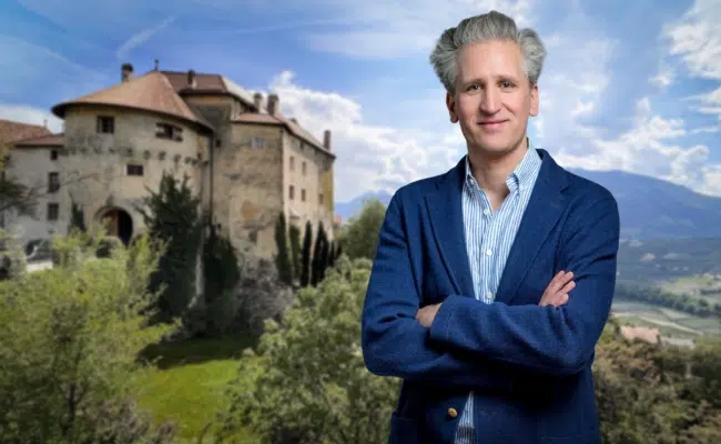 Johann-Philipp Spiegelfeld mit verschränkten Armen vor einem Schloss.