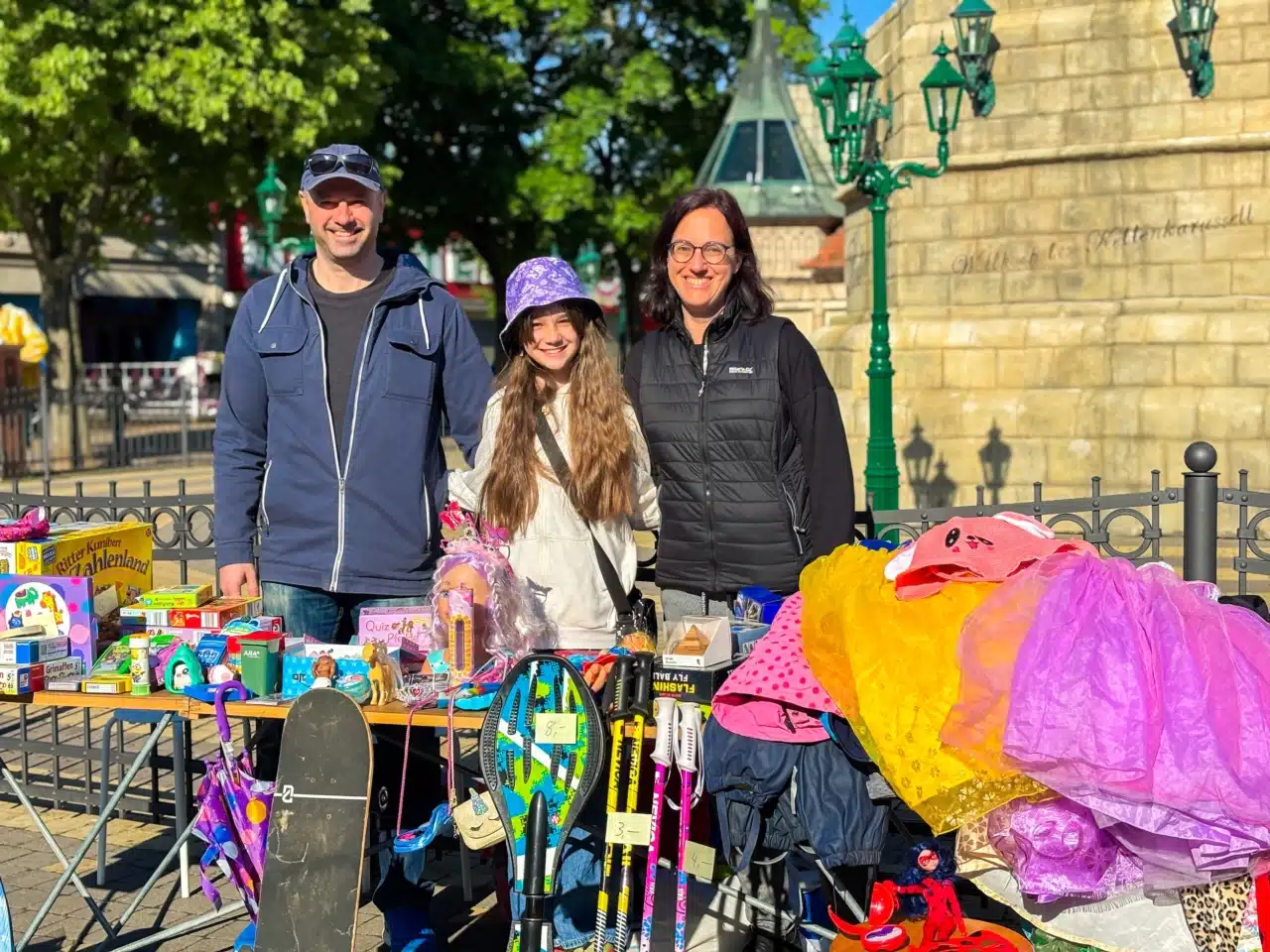 Familie hinter einem Flohmarktstand mit gebrauchtem Spielzeug und Kinderkleidung im Wiener Prater