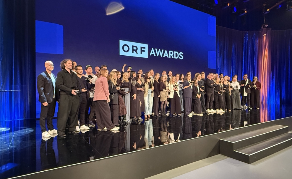 Die Gewinnerteams stehen mit ihren Trophäen auf der blau beleuchteten Bühne vor dem Schriftzug „ORF AWARDS“.