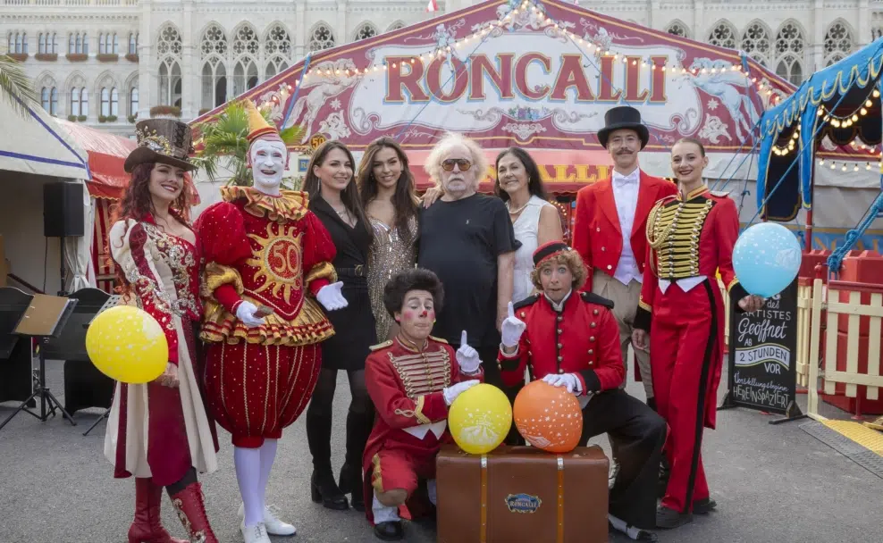 Familie Paul und Mitglieder des Roncalli-Ensembles mit bunten Luftballons vor dem Circuseingang am Wiener Rathausplatz.