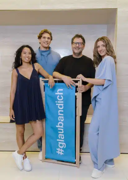 Valerie Valdez, Wieland Lackinger, Martin Radjaby-Rasset und Toni Gohl posieren rund um einen blauen #glaubandich-Liegestuhl.