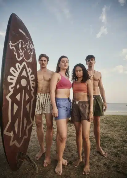 Wieland Lackinger, Toni Gohl, Valerie Valdez und Basti Felver stehen mit einem Surfboard am Neusiedlersee.