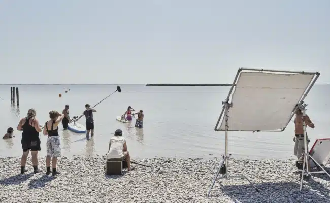 Ein Filmteam dreht mit Tonangel und Reflektor eine Szene mit zwei Darstellerinnen im seichten Wasser des Neusiedlersees.