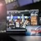Smartphone mit „Servus Nachrichten in 90 Sekunden“ vor einem Bildschirm im ServusTV-Sendestudio