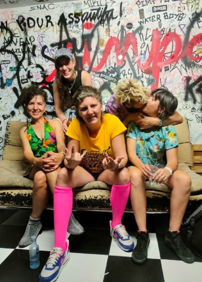 Die argentinische Band Kumbia Queers sitzt gemeinsam vor einer bemalten Wand