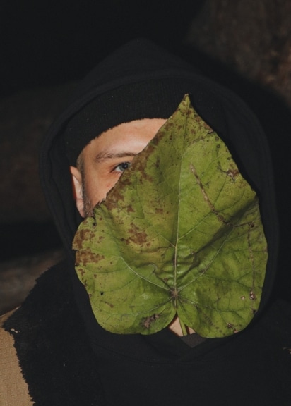Der österreichische Act Kurpark hält ein großes Blatt vor das Gesicht