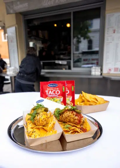 Zwei Portionen Wiener Nacho Dog mit Tortilla-Chips auf einem Tablett vor dem Würstelstand „Alles Wurscht“.