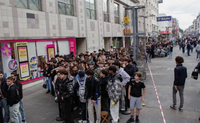 Zahlreiche Menschen stehen entlang der Favoritenstraße vor Loco Chicken in einer Warteschlange.