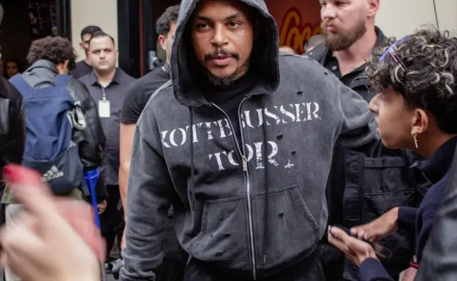 Luciano im dunklen Kapuzenpullover zwischen Menschen vor dem Wiener Loco-Chicken-Restaurant.