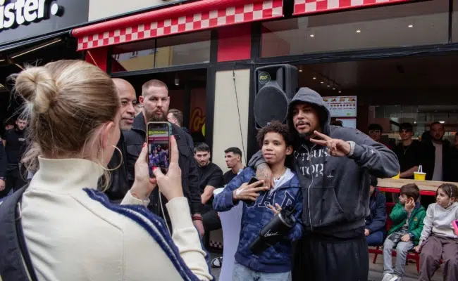 Luciano hält vor Loco Chicken in Wien ein Mikrofon, während Fans die Szene mit Smartphones festhalten.