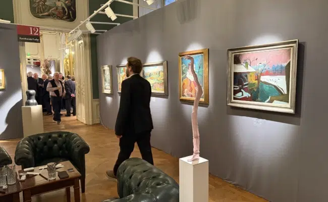 Gemälde an grauen Ausstellungswänden und Skulpturen auf Sockeln zwischen Ledersesseln in den historischen Räumen des Palais Esterházy.