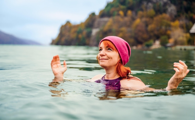 Eine Frau mit roter Mütze beim Kaltbaden im See.