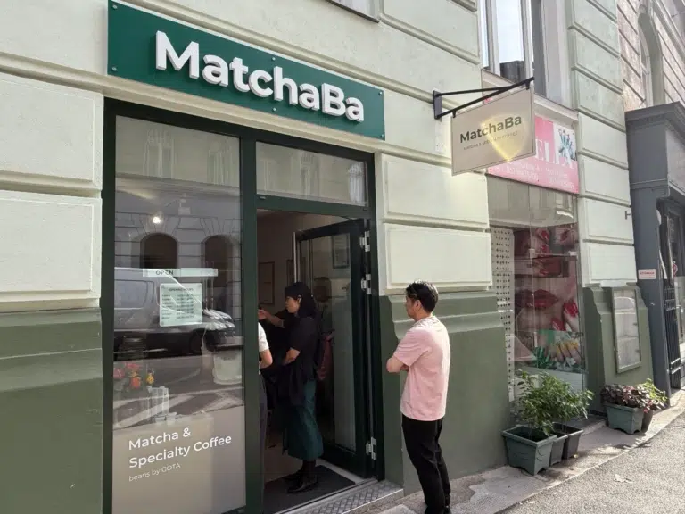Eingang der MatchaBa mit grünem Schriftzug und dem Fensterhinweis „Matcha & Specialty Coffee“ in der Otto-Bauer-Gasse.