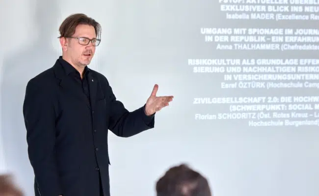 Thomas Goiser spricht vor der projizierten Programmübersicht zum Publikum.